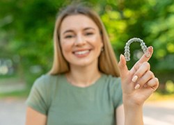 Smiling patient holding clear aligner
